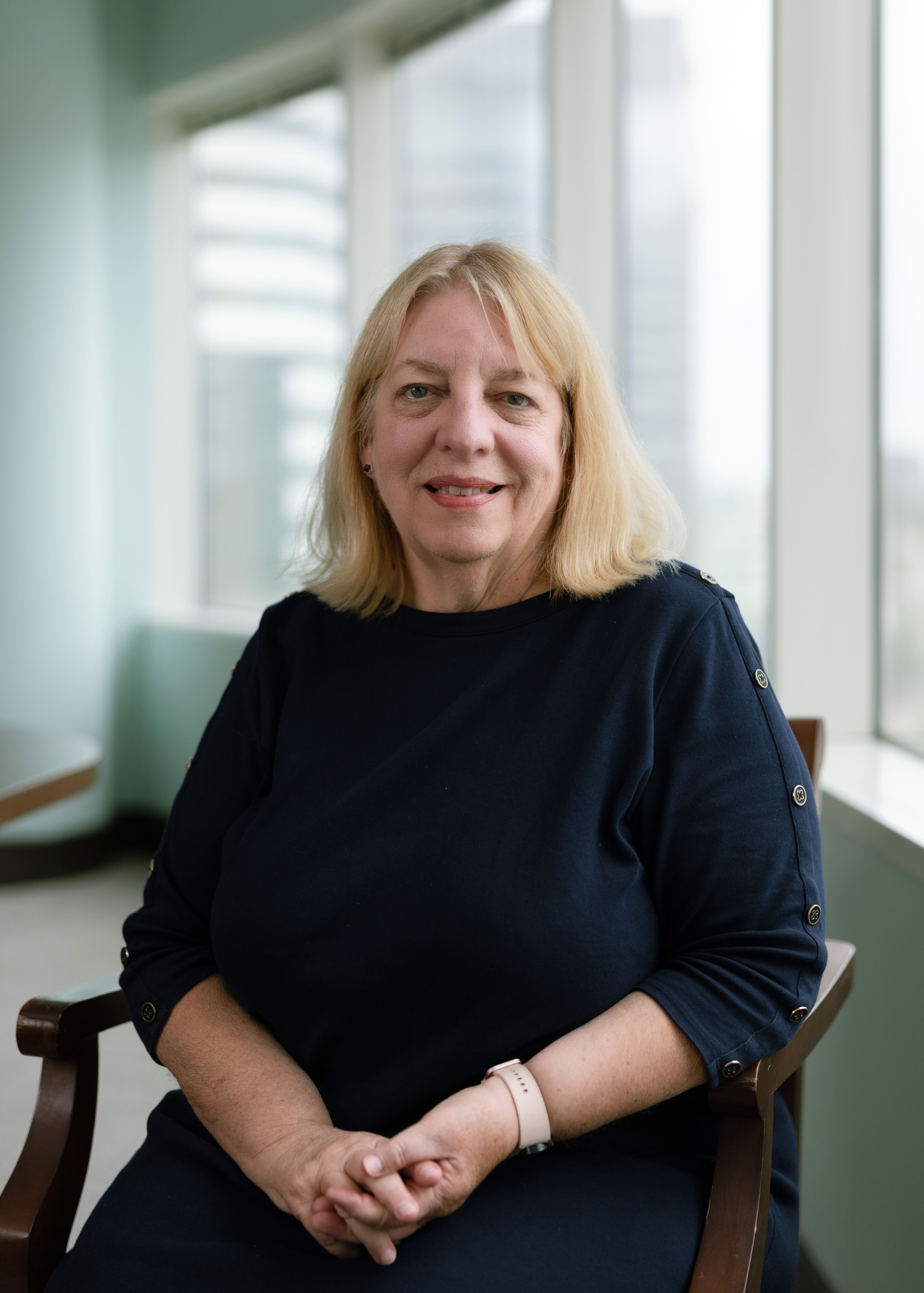 A woman seated in chair with black top