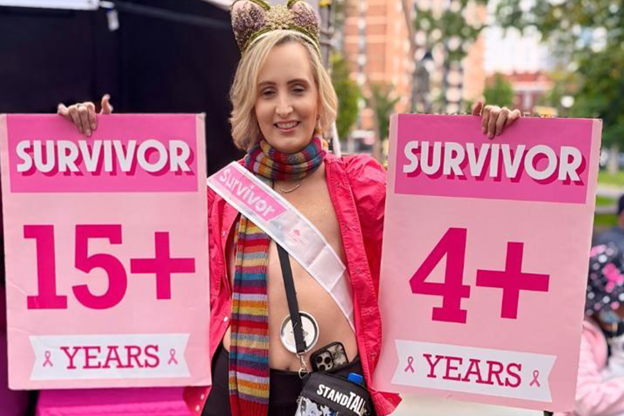 Beth Rutherford standing with two breast cancer signs